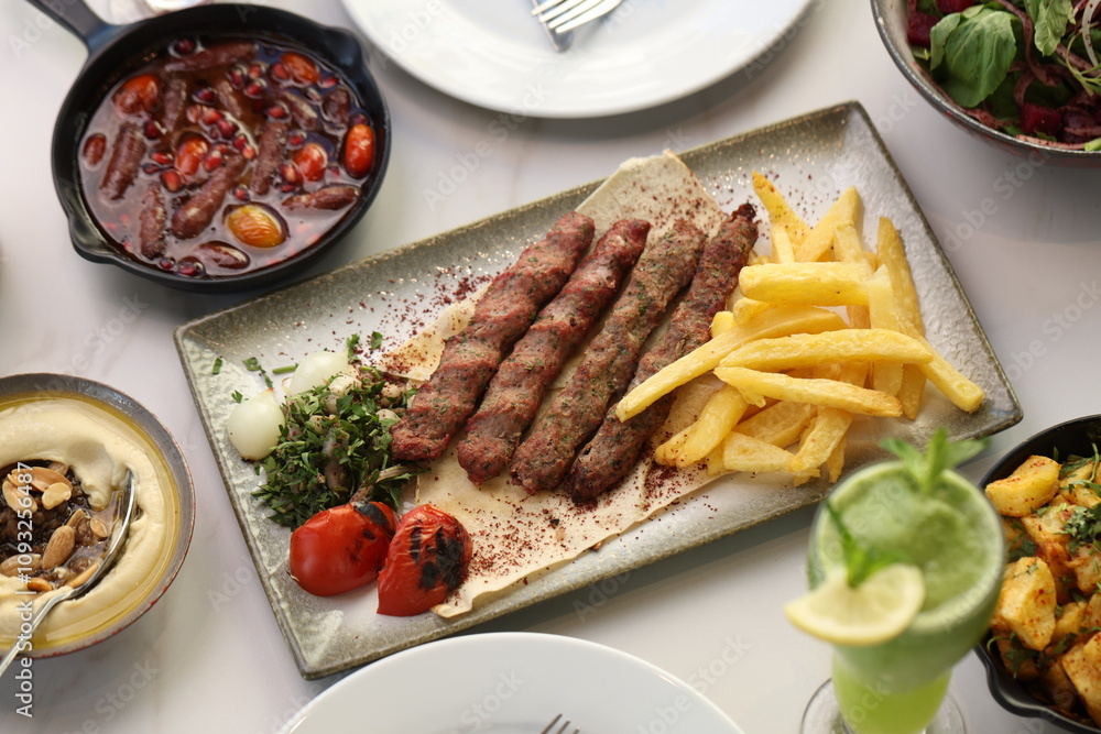 A platter of chargrilled Lebanese beef kebabs served with crispy French fries, grilled tomatoes, onions, fresh parsley, and sumac seasoning on flatbread, offering a hearty and flavorful Middle Eastern A platter of chargrilled Lebanese beef kebabs served with crispy French fries, grilled tomatoes, onions, fresh parsley, and sumac seasoning on flatbread, offering a hearty and flavorful Middle Eastern