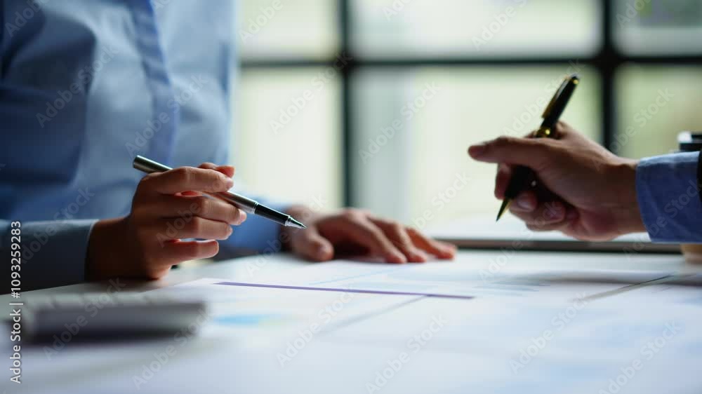 Business partners reviewing a contract and preparing to finalize an agreement in a professional office setting Business partners reviewing a contract and preparing to finalize an agreement in a professional office setting