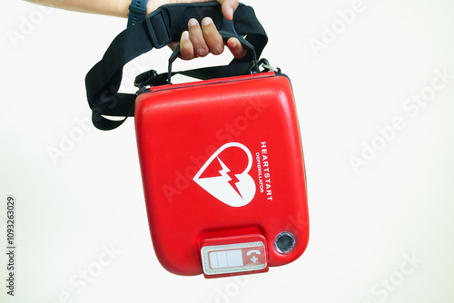 Foto Male hand holding AED or defibrillator Red machine on white background