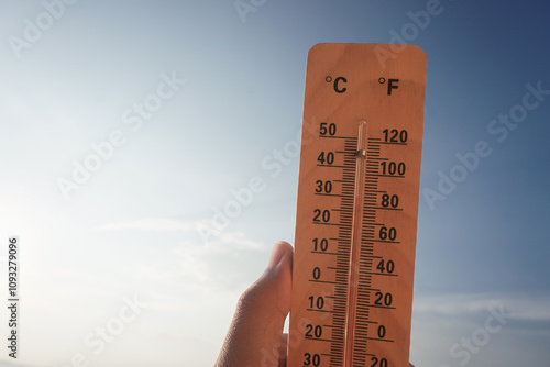 Celsius and fahrenheit scale thermometer shows plus 30 degrees during midday in Asia with sky background. The thermometer shows temperatures above 30 degrees in summer