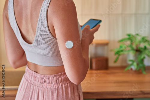 Young girl with diabetes uses smart remote sensor for monitoring of blood sugar level at home, modern active diabetic lifestyle