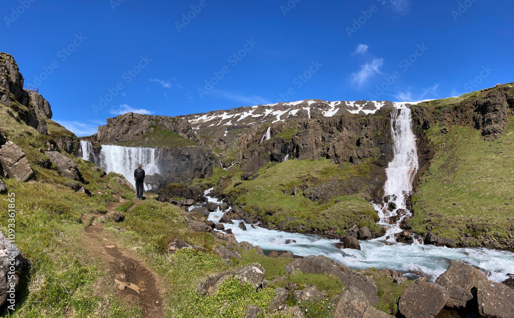 male hiker in rugged icelandic landscape next to a mountain river with several cascades male hiker in rugged icelandic landscape next to a mountain river with several cascades