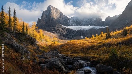 Majestic autumn mountain vista featuring vibrant foliage, rocky stream, and towering peaks under a partly cloudy sky.