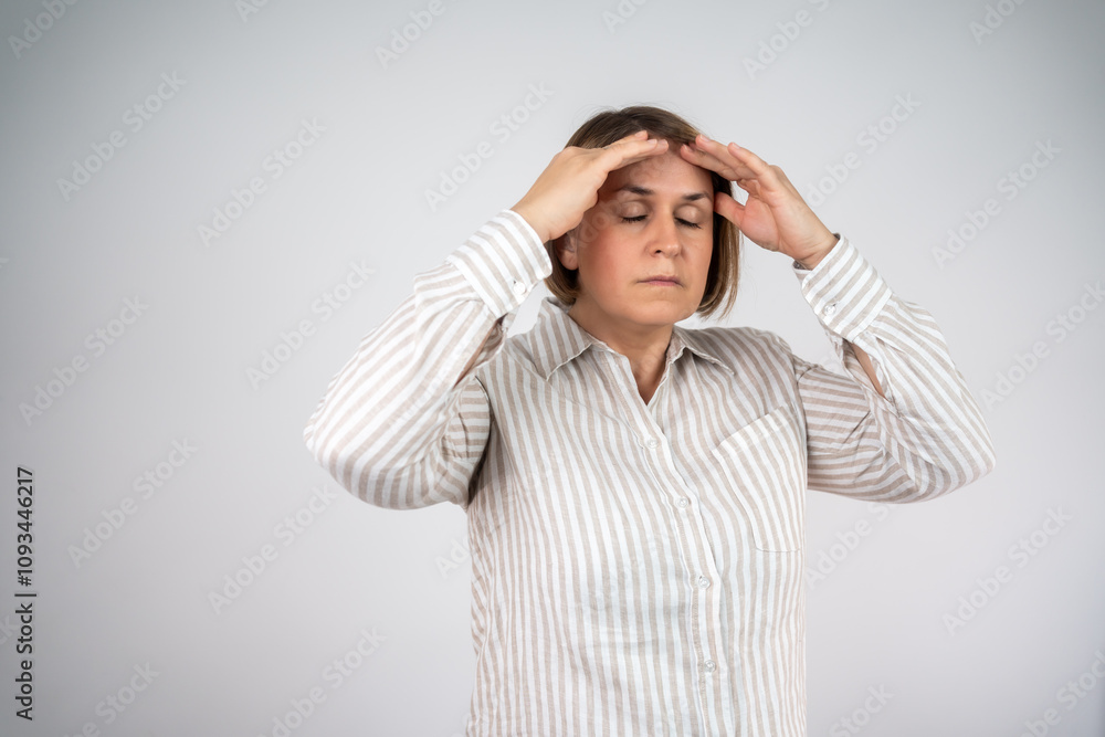 Woman overwhelmed with stress and concern, confusion and doubt, hands to head, on grey background copy space. Mature woman standing in front of an isolated background, looking stressed. Woman overwhelmed with stress and concern, confusion and doubt, hands to head, on grey background copy space. Mature woman standing in front of an isolated background, looking stressed.