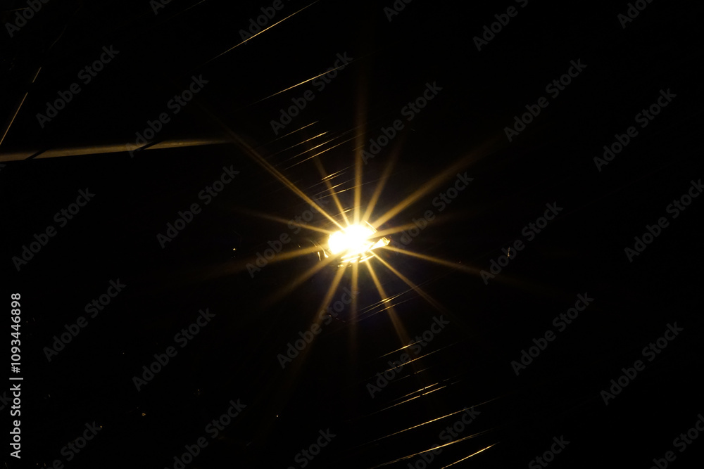 Streetlights shine on the road at night, beams of light on a black background.
Streetlights shine on the road at night, beams of light on a black background.