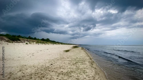 Slow motion, zwolnione tempo. Ciemne, burzowe, ciężkie chmury na plaży nad Bałtykiem. Plaża nad morzem, lato. Pusta plaża, bez ludzi.	 photo