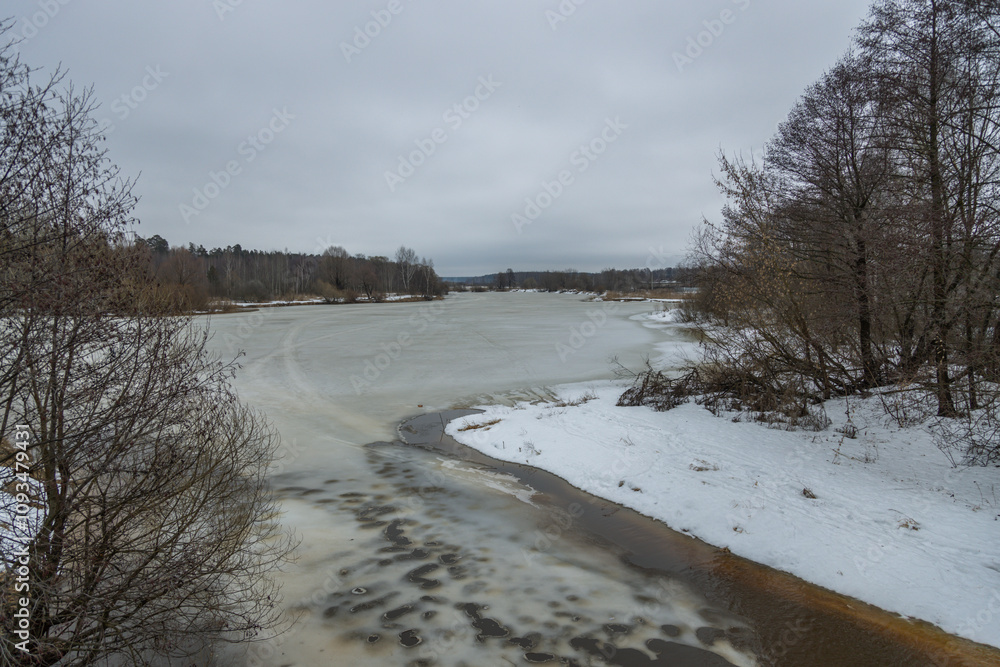 River with a frozen bank and a cloudy sky in the background River with a frozen bank and a cloudy sky in the background
