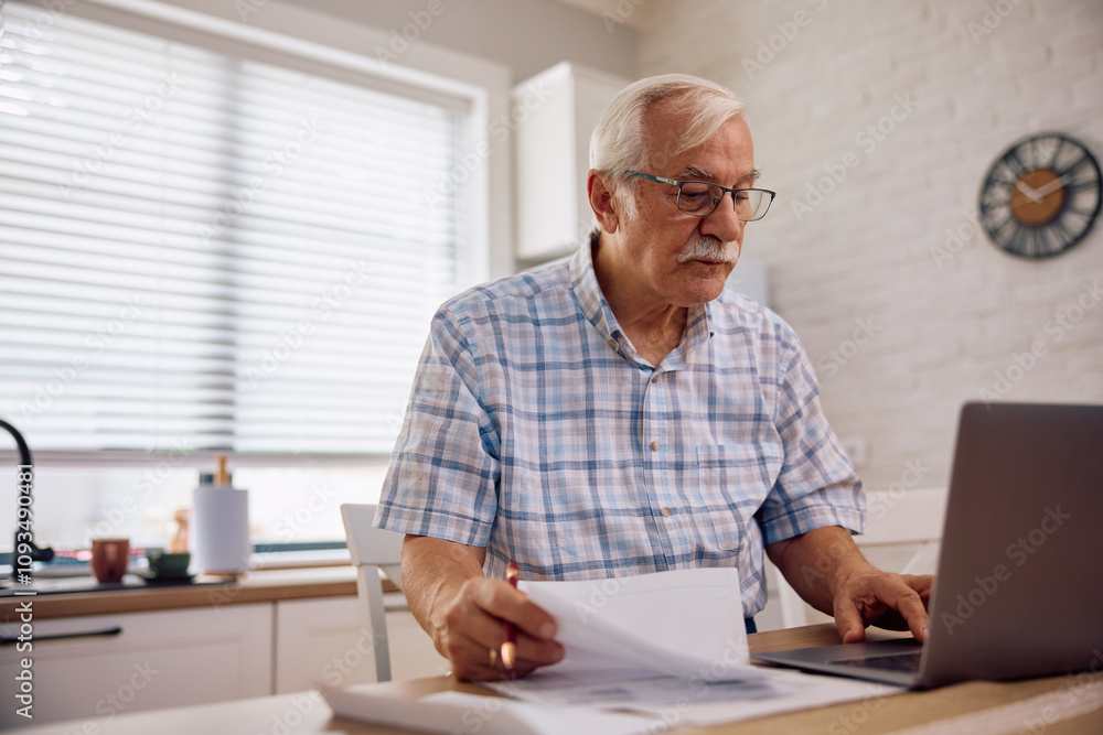 Senior man using laptop while analysing financial bills at home. Senior man using laptop while analysing financial bills at home.