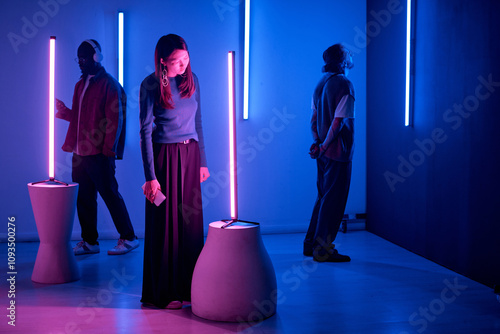 Obraz na plátně Individuals observing light sculptures in modern art gallery with neon blue and