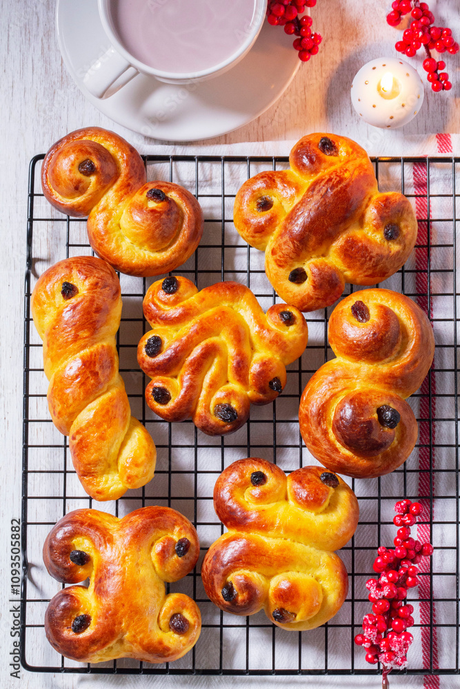 Traditional saffron Swedish buns lussekatt in different shapes, served with cocoa on a wooden table. Buns for St. Lucia's Day.