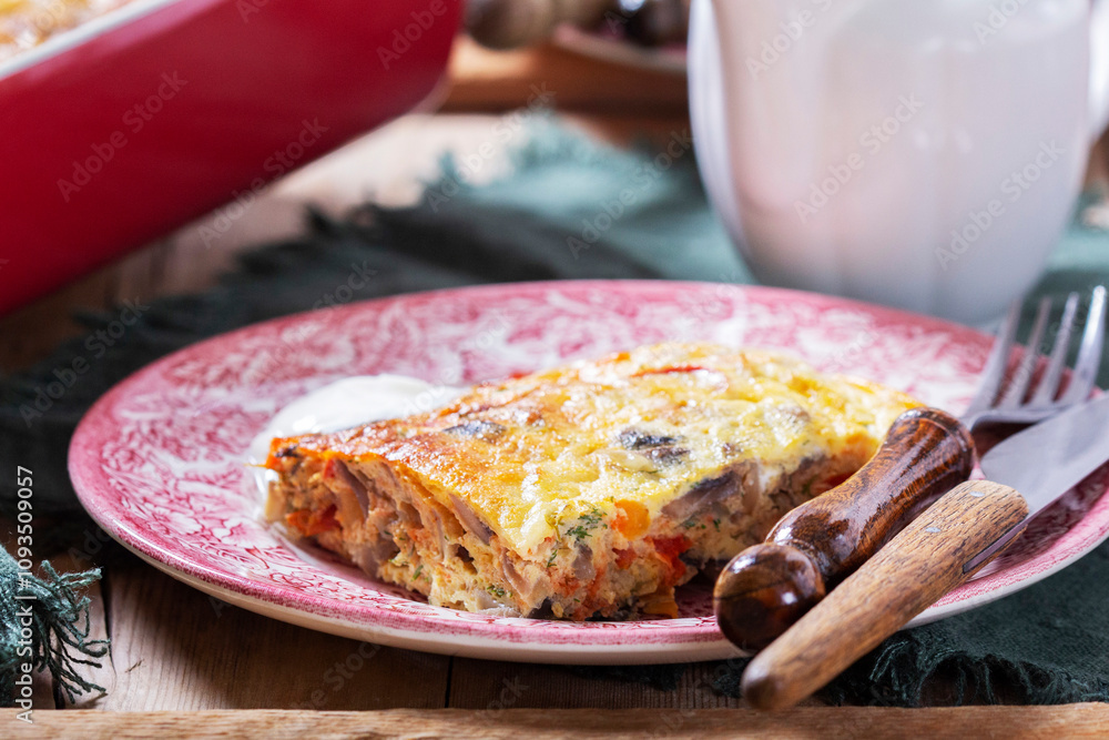 Oven baked omelette with vegetables served with sour cream on wooden background.