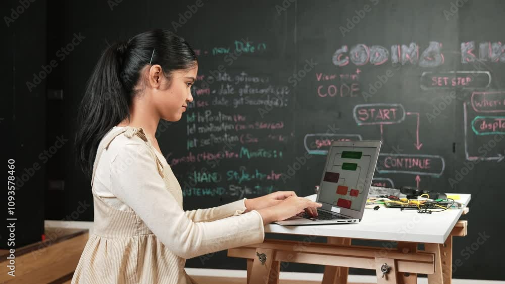 high school girl writing code or engineering prompt while attend in STEM technology class. Teenager coding or programming system while looking at computer screen in front of blackboard. Edification high school girl writing code or engineering prompt while attend in STEM technology class. Teenager coding or programming system while looking at computer screen in front of blackboard. Edification