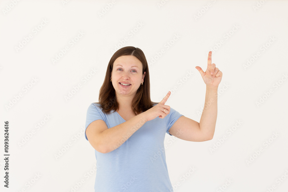 Hey look. Smiling pretty female model pointing fingers right at empty space and inviting to check it out, showing advertisement on white background. Hey look. Smiling pretty female model pointing fingers right at empty space and inviting to check it out, showing advertisement on white background.