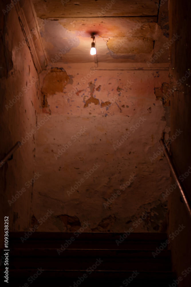 A single lightbulb shining above a creepy dark staircase A single lightbulb shining above a creepy dark staircase