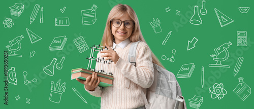 Little schoolgirl with molecular model, books and backpack on green background