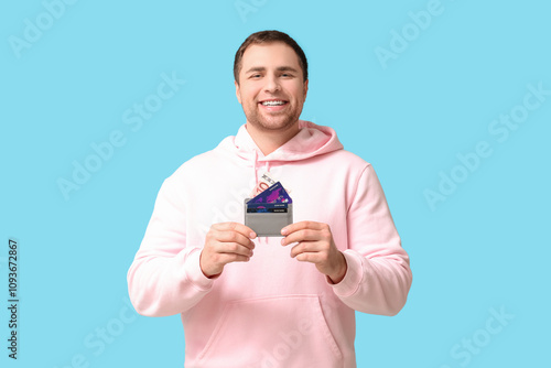 Happy young man with credit cards on blue background photo