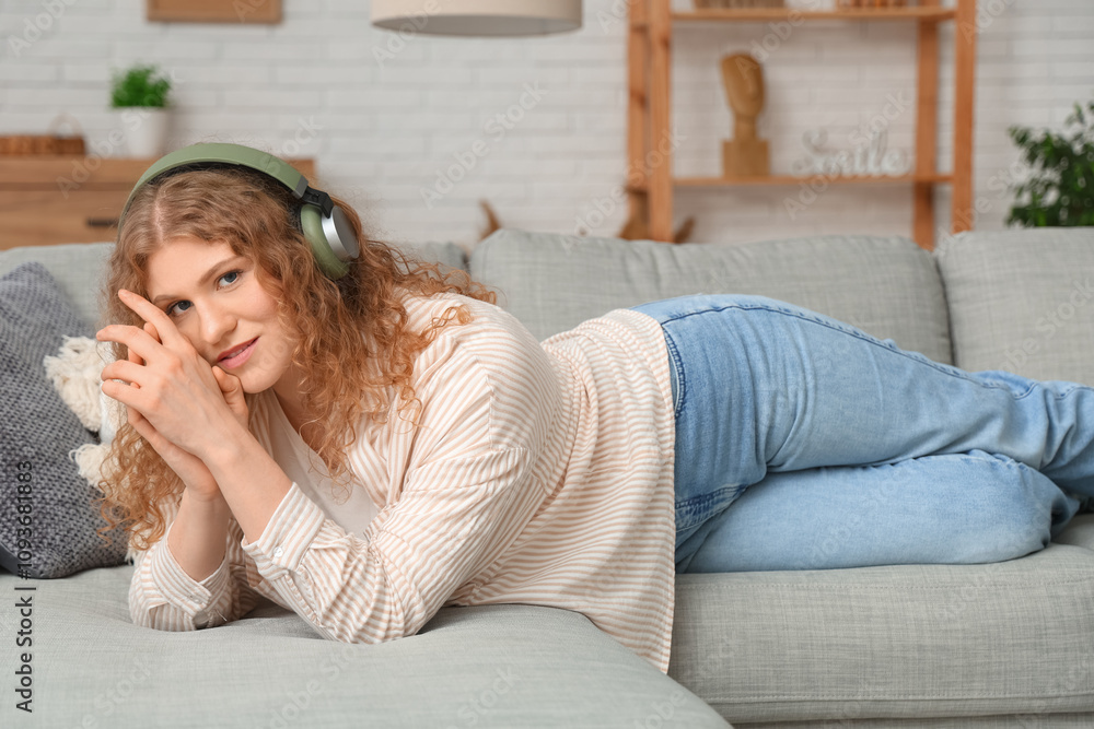 Obraz premium Young woman in headphones lying on sofa at home