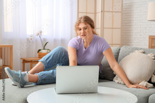 Young woman sitting on sofa...