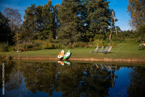 Serene Lakeside Scene with Kayaks and Lounge Chairs on Grassy Bank photo