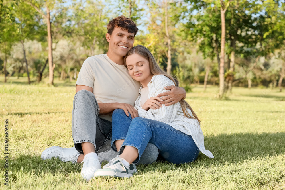 Beautiful young happy couple sitting in summer park Beautiful young happy couple sitting in summer park