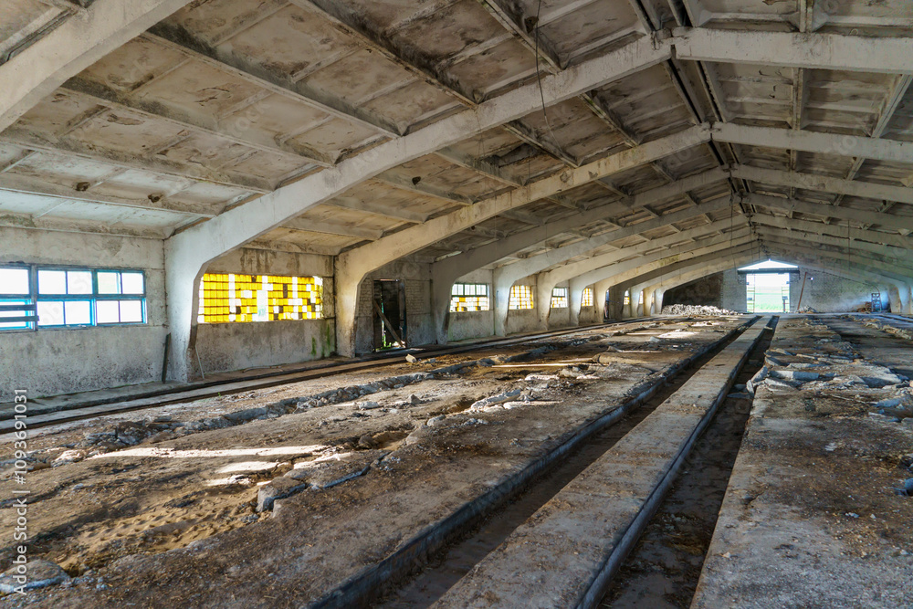 An abandoned destroyed barn, cowshed, warehouse or hangar from the inside. An old abandoned concrete bunker. Ammunition depot from inside in low light An abandoned destroyed barn, cowshed, warehouse or hangar from the inside. An old abandoned concrete bunker. Ammunition depot from inside in low light