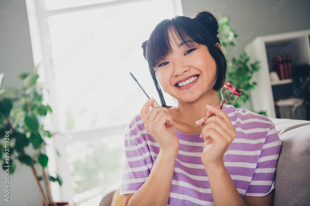 Photo of pretty cheerful lady wear striped violet t-shirt applying mascara indoors room home house Photo of pretty cheerful lady wear striped violet t-shirt applying mascara indoors room home house