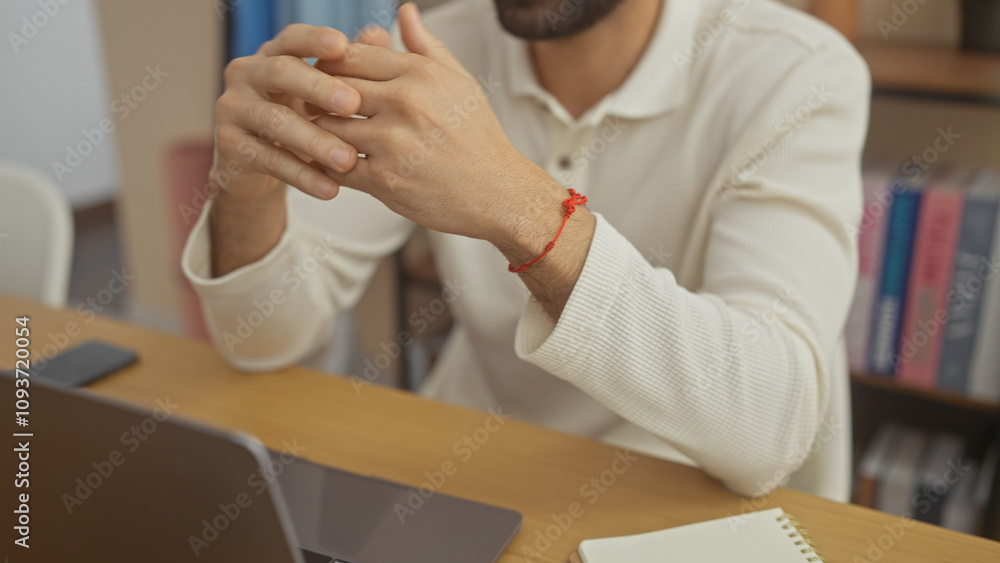 A young hispanic man with a beard in a casual white shirt sits at a home office with a laptop and notebook, radiating a professional yet relaxed vibe. A young hispanic man with a beard in a casual white shirt sits at a home office with a laptop and notebook, radiating a professional yet relaxed vibe.