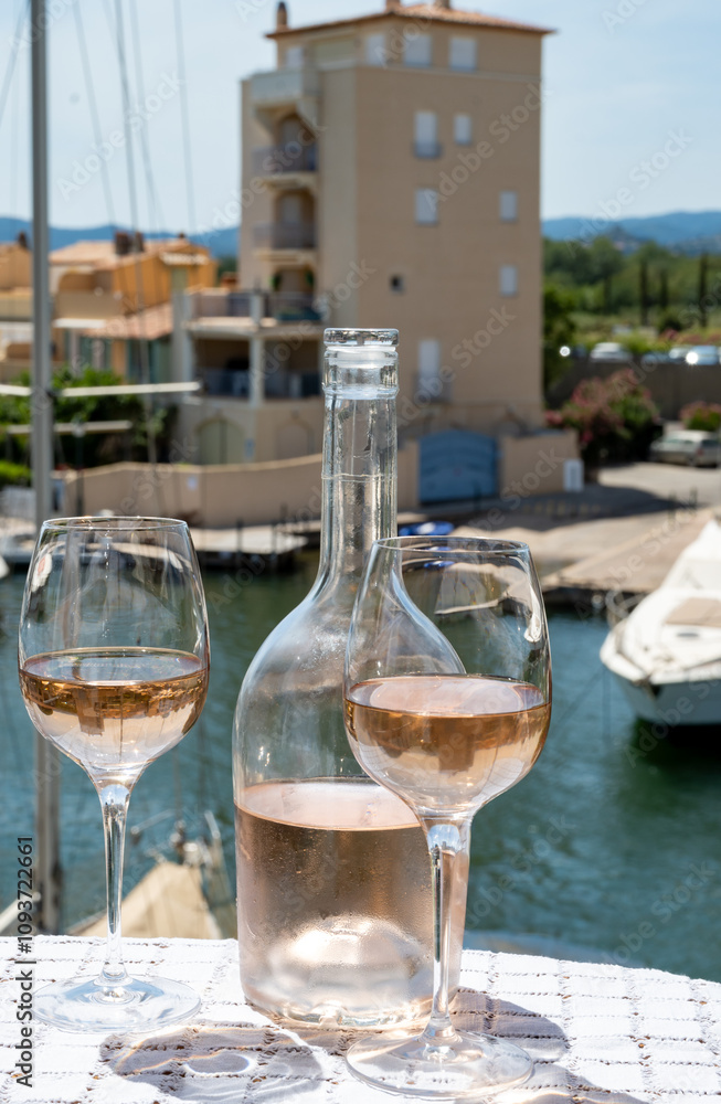 Obraz premium Glasses of cold rose gris Cote de Provence wine in yacht harbour of Port Grimaud, summer vacation on French Riviera in Provence, France