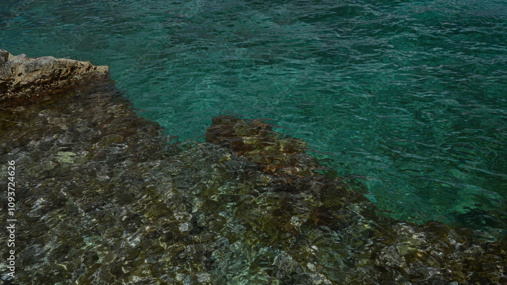 A tranquil view of clear turquoise water near rocky shores in torre dell'orso, salento, puglia, italy, europe showcasing natural beauty and serenity. A tranquil view of clear turquoise water near rocky shores in torre dell'orso, salento, puglia, italy, europe showcasing natural beauty and serenity.