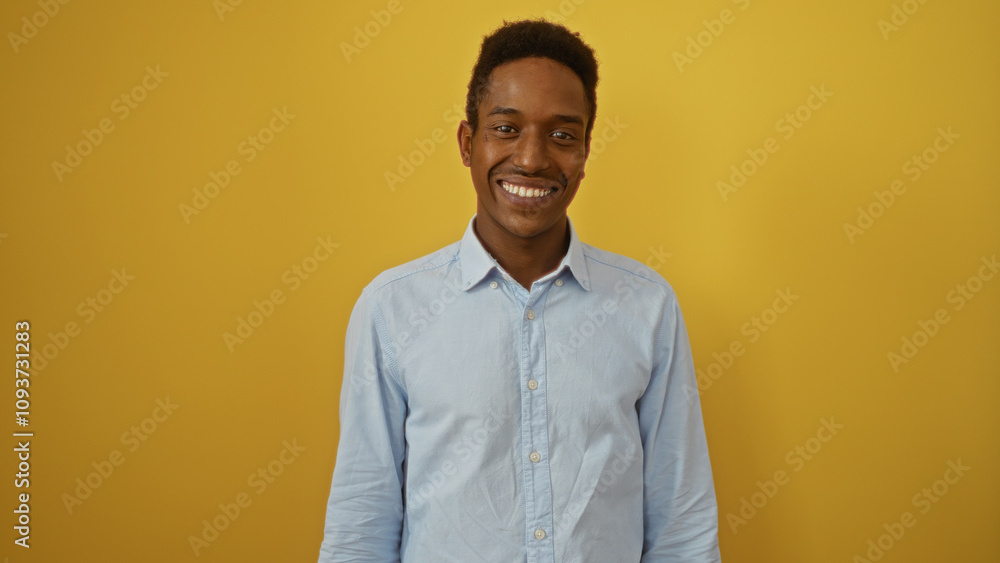 Young man smiling against isolated yellow background showcasing an attractive and friendly demeanor in a casual setting. Young man smiling against isolated yellow background showcasing an attractive and friendly demeanor in a casual setting.