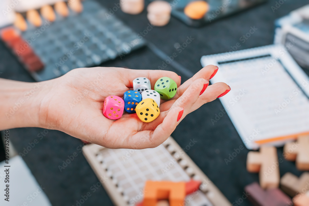 A hand holding colorful dice, symbolizing the concept of tabletop games, statistics, and probability.