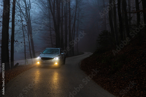 Car driving on mountain road on foggy evening photo