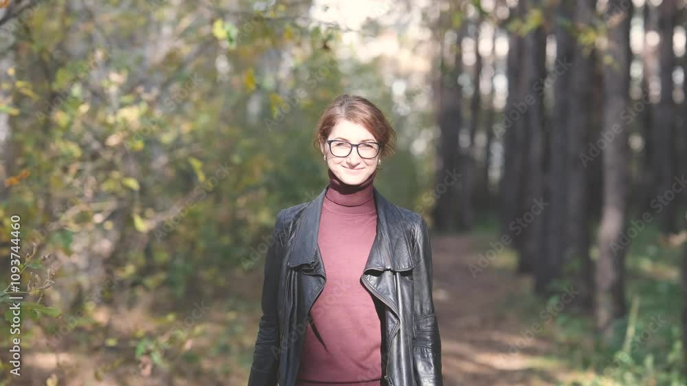 Smiling city woman relaxing in the forest. Thoughtful woman in glasses and office clothes walking in the autumn park, breathing fresh air, enjoying nature. Smiling city woman relaxing in the forest. Thoughtful woman in glasses and office clothes walking in the autumn park, breathing fresh air, enjoying nature.
