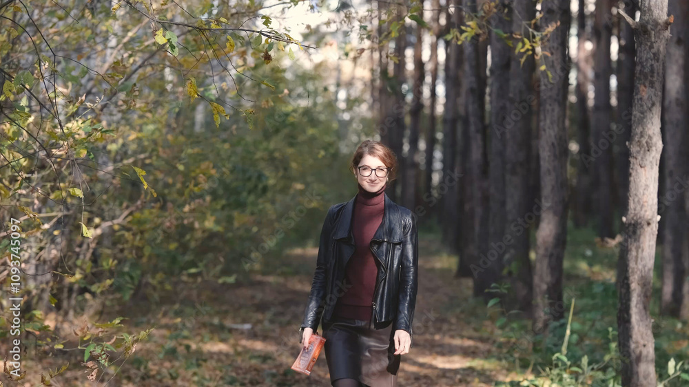 Smiling city woman relaxing in the forest. Thoughtful woman in glasses and office clothes walking in the autumn park, breathing fresh air, enjoying nature. Smiling city woman relaxing in the forest. Thoughtful woman in glasses and office clothes walking in the autumn park, breathing fresh air, enjoying nature.