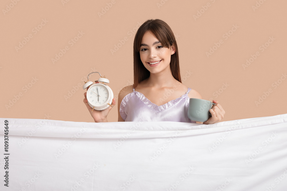 Beautiful young woman with alarm clock, cup of coffee and sheet on beige background