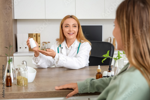 Female homeopathic doctor giving pills to patient at table in office