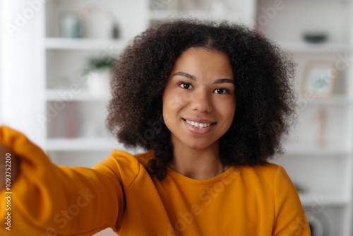 Closeup Of Cheerful Young African American Female Taking Selfie At Home, Joyful Black Woman Smiling At Camera While Capturing Self-Portrait, Happy Lady Relaxing On Couch In Living Room. High quality