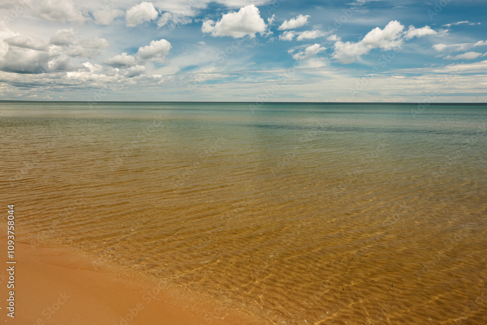 Obraz premium Soft, wispy clouds float over the calm waters of Lake Michigan off the beach at Harrington Beach State Park, Belgium, Wisconsin in late June