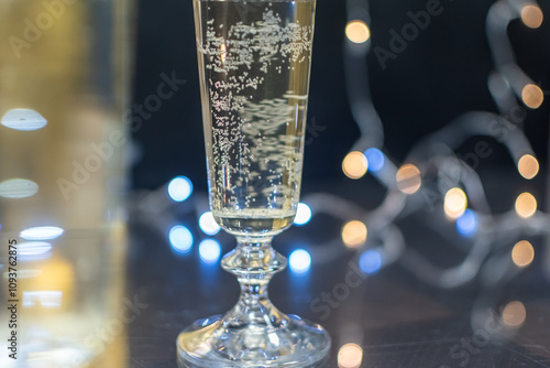 Сhampagne glass with bubbles inside close-up on blurred festive background with multicolored lights photo