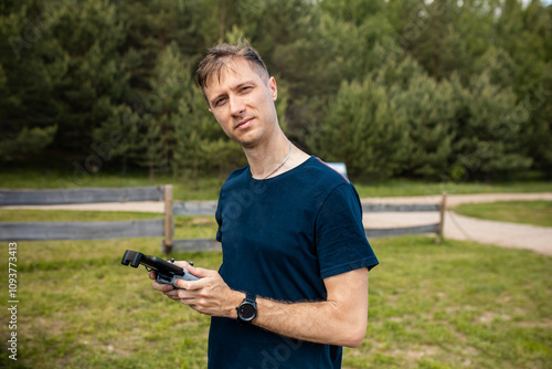 Man Operating Drone Controller in Grassy Area with Dense Trees photo