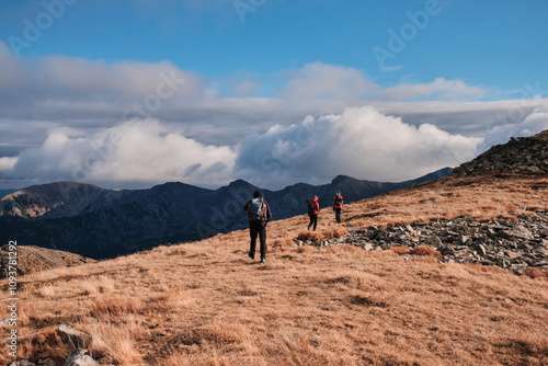 Hikers trek across a scenic mountain ridge under a dramatic, cloudy sky. Breathtaking panoramic view. Perfect for travel, adventure, and outdoor themes. photo