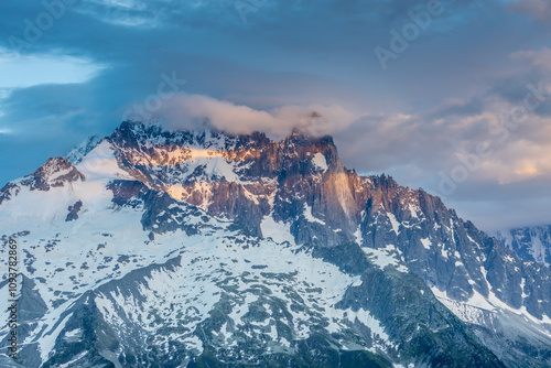 Petit Dru granite mountain wall and summit in Chamonix valley, french Alps. Prominent mountain peak in the Alps, stunning landscape view of the rocky peak covered with clouds, snow and ice