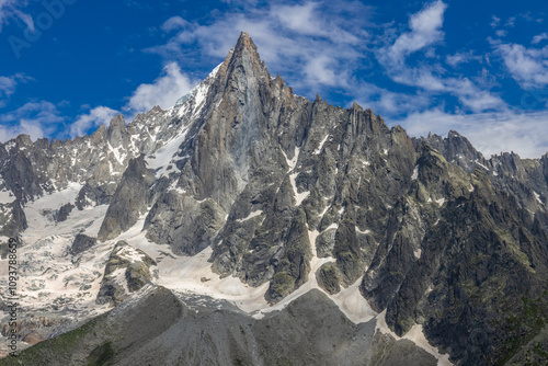 Petit Dru granite mountain wall and summit in Chamonix valley, french Alps. Prominent mountain peak in the Alps, stunning landscape view of the rocky peak covered with clouds, snow and ice