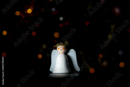 Decorative DIY Christmas Angel figure. Dark background with defocused lights in different colors. Creative Christmas and Easter concept. Placed in the middle of the frame.