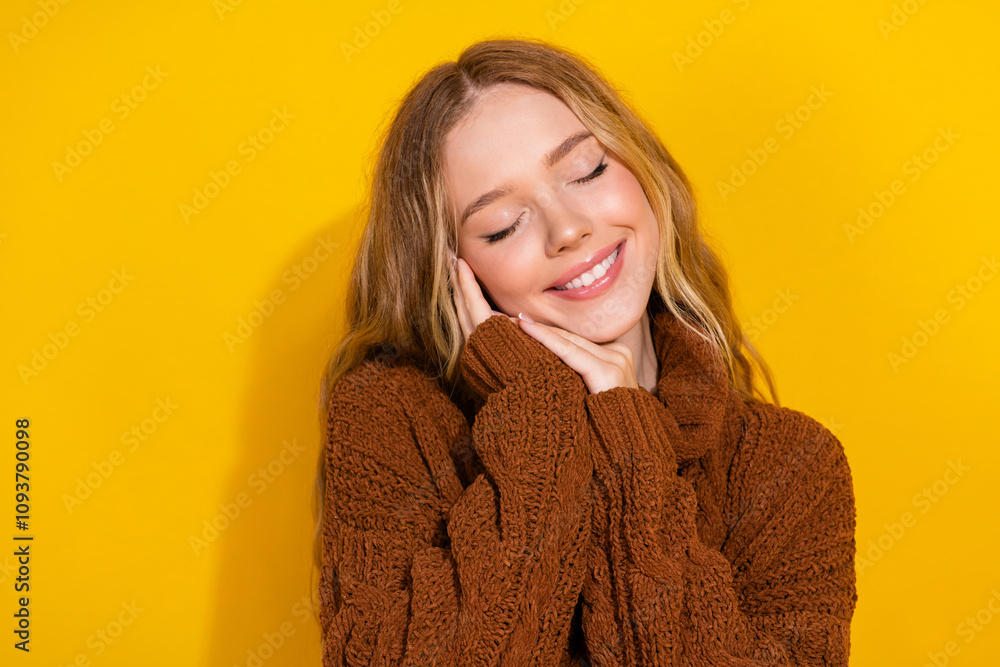 Photo of lovely young girl closed eyes hands touch cheek empty space wear pullover isolated on yellow color background Photo of lovely young girl closed eyes hands touch cheek empty space wear pullover isolated on yellow color background