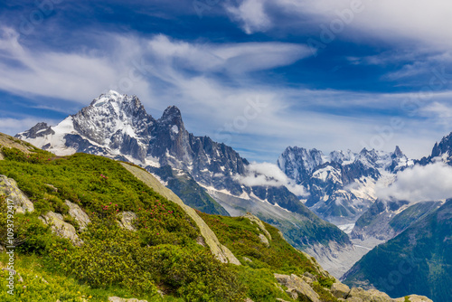 Petit Dru granite mountain wall and summit in Chamonix valley, french Alps. Prominent mountain peak in the Alps, stunning landscape view of the rocky peak covered with clouds, snow and ice