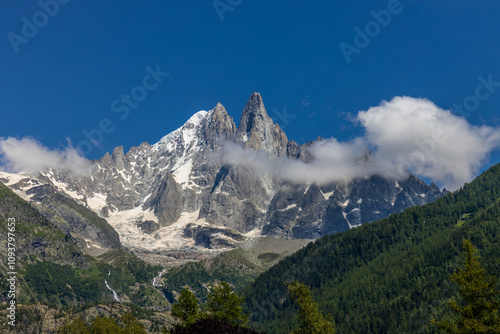 Petit Dru granite mountain wall and summit in Chamonix valley, french Alps. Prominent mountain peak in the Alps, stunning landscape view of the rocky peak covered with clouds, snow and ice