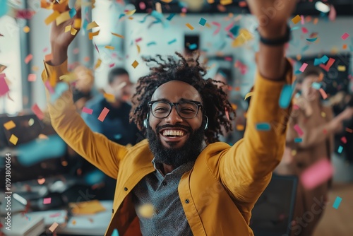 Joyful man celebrating in an office environment with colorful confetti falling around him, expressing happiness and positivity among colleagues