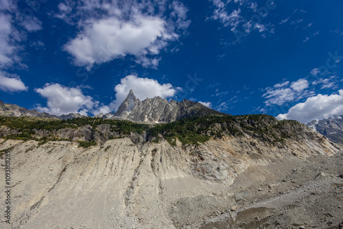 Petit Dru granite mountain wall and summit in Chamonix valley, french Alps. Prominent mountain peak in the Alps, stunning landscape view of the rocky peak covered with clouds, snow and ice