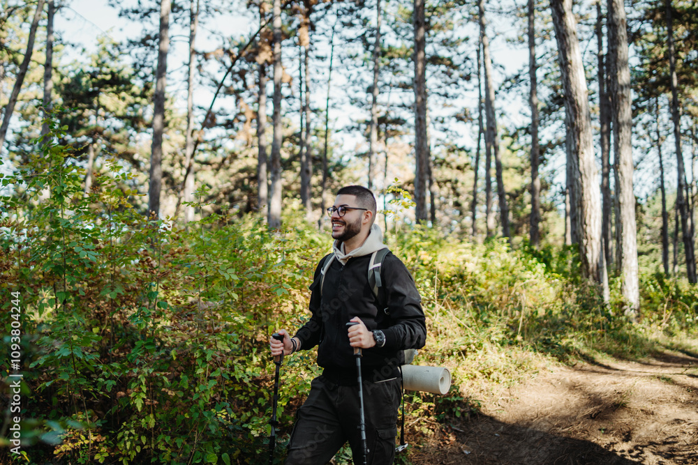 Fototapeta premium Young caucasian man hiking or trekking through the forest
